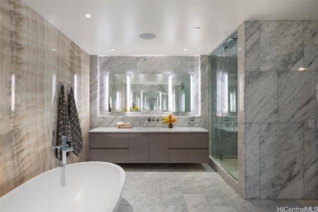 bathroom with vanity, shower with separate bathtub, and tile walls