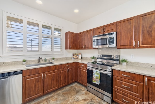 kitchen featuring appliances with stainless steel finishes, sink, and light stone countertops