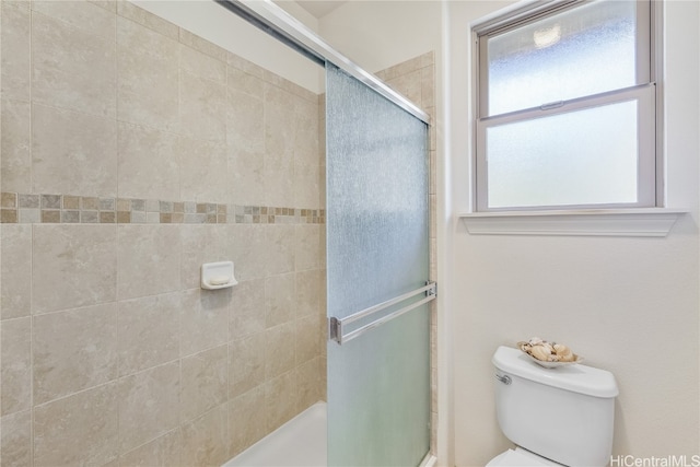 bathroom with a shower with shower door and toilet