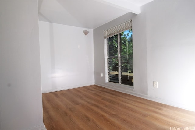 unfurnished room with hardwood / wood-style flooring and beamed ceiling