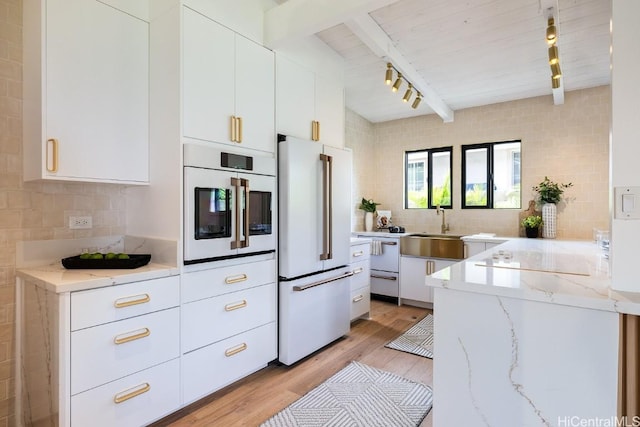 kitchen with white cabinets, light stone countertops, white appliances, and rail lighting