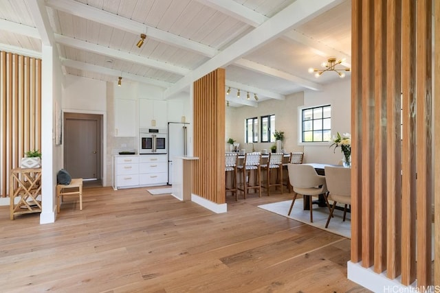 interior space with white cabinets, beam ceiling, light hardwood / wood-style flooring, and oven