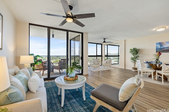 living room with expansive windows, hardwood / wood-style flooring, and ceiling fan