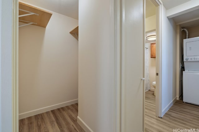 hall featuring stacked washer and dryer and light wood-type flooring