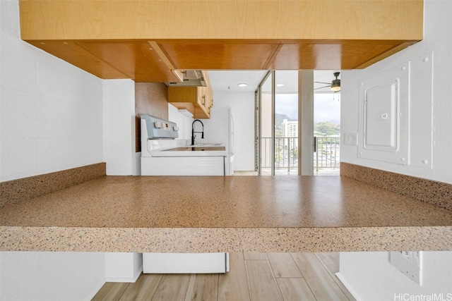 kitchen with light wood-type flooring, ceiling fan, and white stove