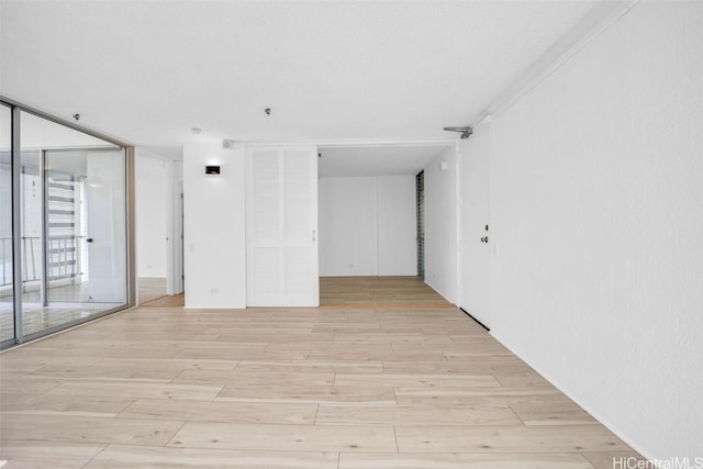 spare room featuring light wood-type flooring and a wall of windows