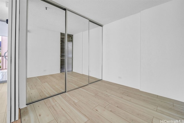 unfurnished bedroom with a closet, light wood-type flooring, and a textured ceiling