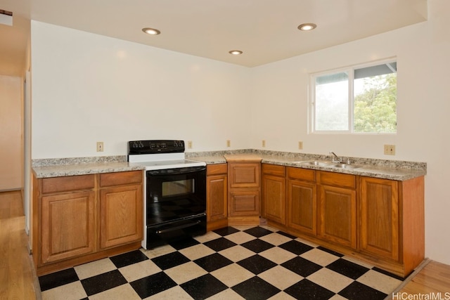 kitchen featuring white range with electric stovetop, light wood-type flooring, and sink