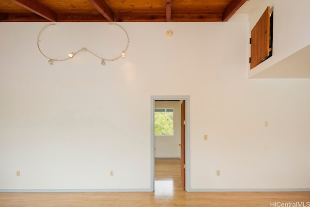 empty room with beamed ceiling, wood ceiling, and light hardwood / wood-style flooring