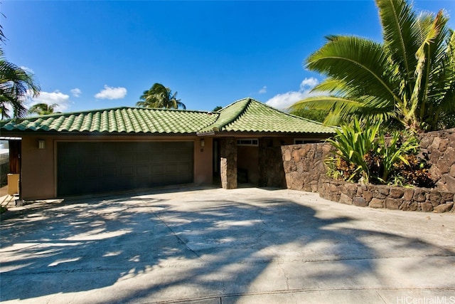 view of front of property featuring a garage, a tiled roof, driveway, and stucco siding