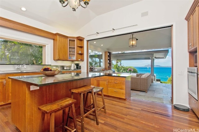 kitchen featuring vaulted ceiling, a kitchen island, oven, a kitchen bar, and a water view