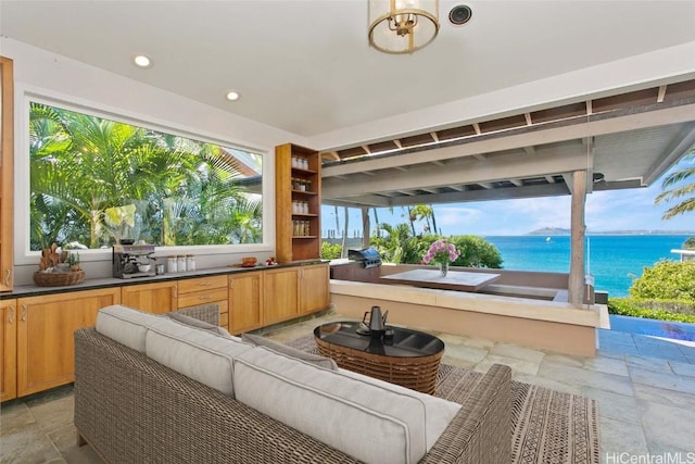 view of patio / terrace featuring a water view, outdoor lounge area, and exterior kitchen