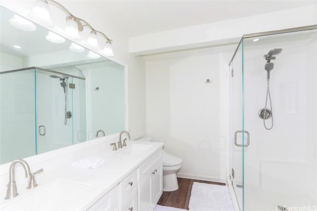 bathroom with a shower with door, vanity, wood-type flooring, and toilet