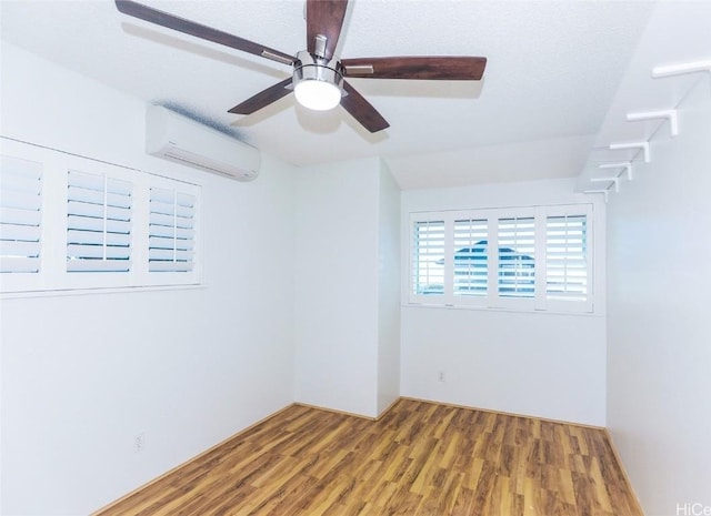 unfurnished room featuring hardwood / wood-style flooring, a wall unit AC, and ceiling fan