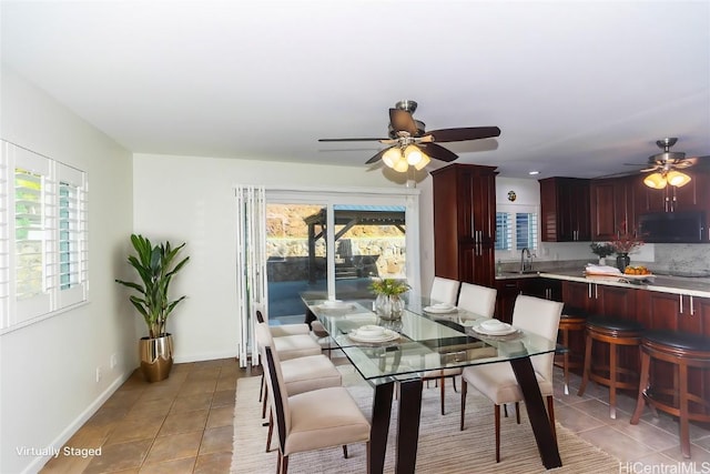 tiled dining space with ceiling fan, a healthy amount of sunlight, and sink