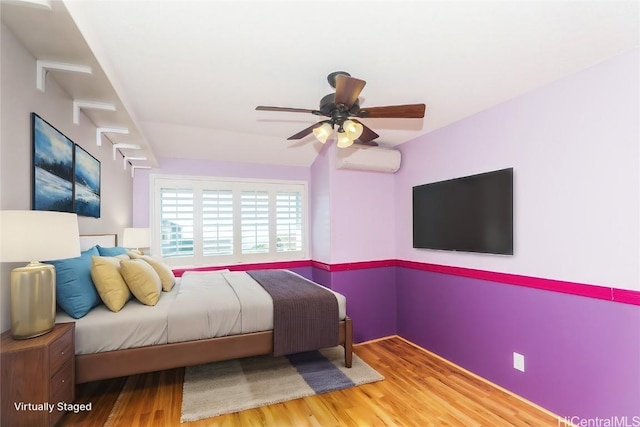 bedroom with a wall mounted AC, ceiling fan, and hardwood / wood-style floors