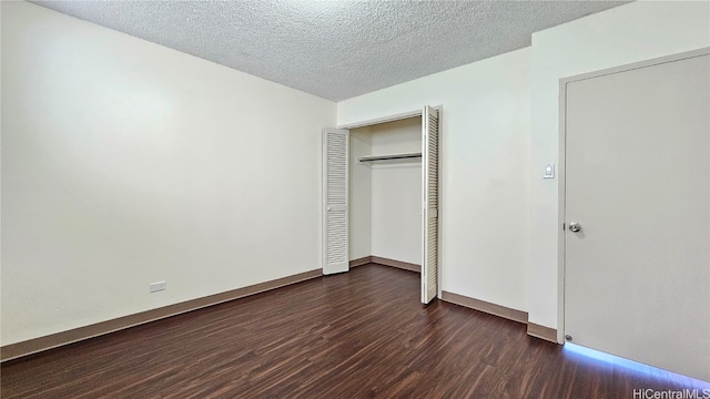 unfurnished bedroom with a textured ceiling, dark hardwood / wood-style floors, and a closet