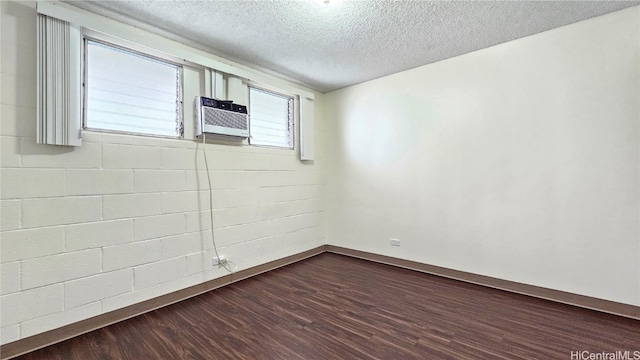 empty room featuring a wealth of natural light, a textured ceiling, cooling unit, and hardwood / wood-style flooring