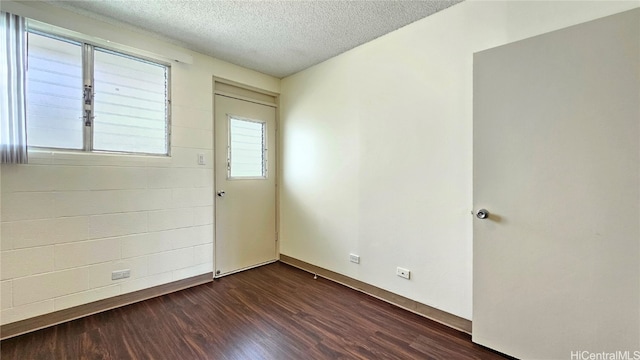 empty room with dark hardwood / wood-style flooring and a textured ceiling