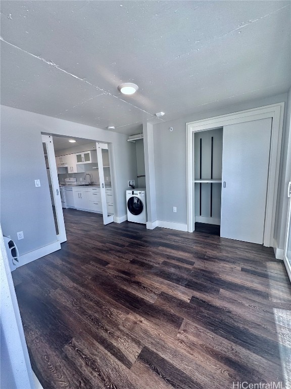 unfurnished living room featuring dark wood-type flooring, washer / clothes dryer, and sink