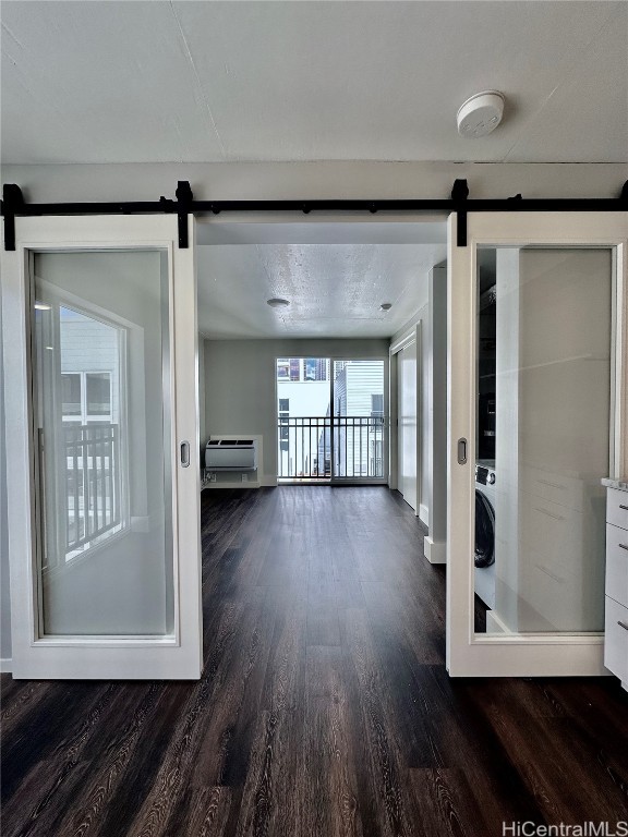 interior space featuring dark wood-type flooring, a barn door, and a textured ceiling