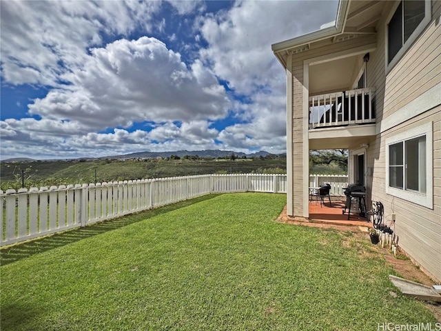 view of yard featuring a patio area, a mountain view, and a balcony