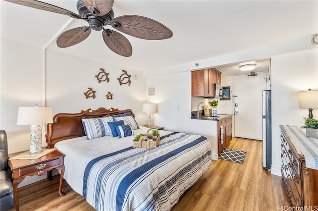 bedroom with ceiling fan, light hardwood / wood-style floors, sink, and stainless steel refrigerator