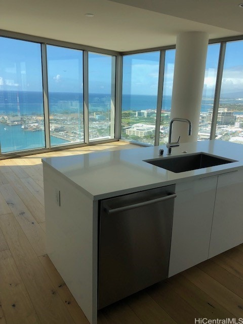 kitchen featuring a wealth of natural light, white cabinetry, light wood-type flooring, and dishwasher