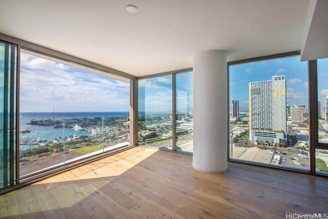 interior space featuring expansive windows, a water view, and hardwood / wood-style flooring