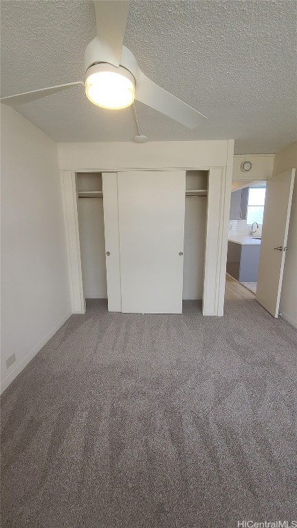 unfurnished bedroom with carpet, a textured ceiling, ceiling fan, and sink