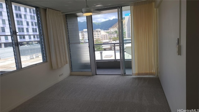 unfurnished room with a mountain view, carpet floors, and ceiling fan