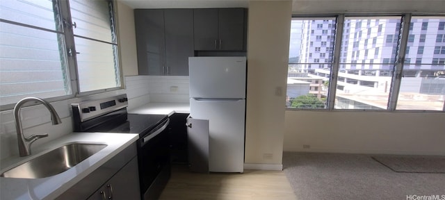 kitchen with light hardwood / wood-style flooring, stainless steel electric range oven, sink, and fridge