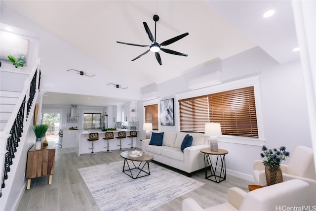 living room featuring a wall unit AC, ceiling fan, and light hardwood / wood-style flooring