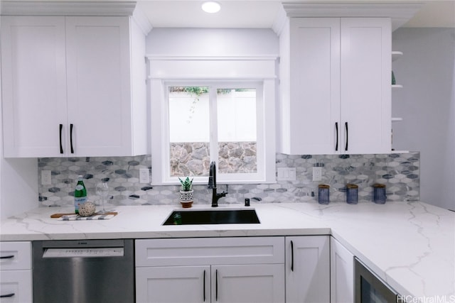 kitchen with white cabinets, tasteful backsplash, stainless steel dishwasher, and sink