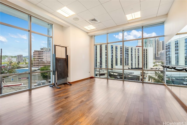 spare room featuring hardwood / wood-style flooring, a wall of windows, and a water view