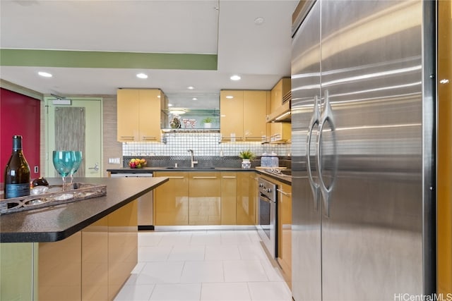 kitchen featuring appliances with stainless steel finishes, tasteful backsplash, light brown cabinets, a center island, and exhaust hood