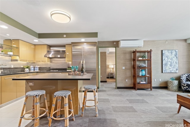 kitchen featuring a breakfast bar, a wall unit AC, backsplash, ventilation hood, and a center island