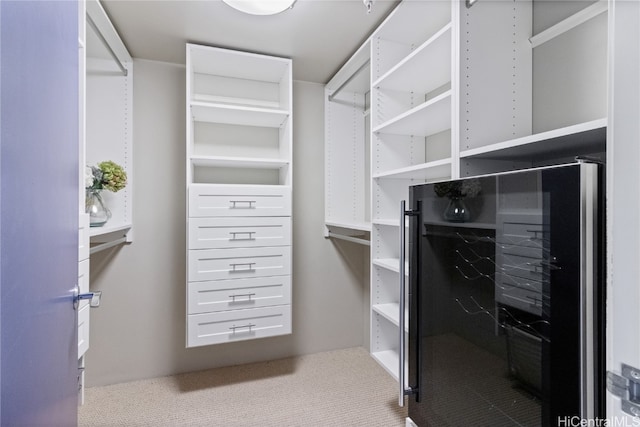 walk in closet featuring beverage cooler and light carpet