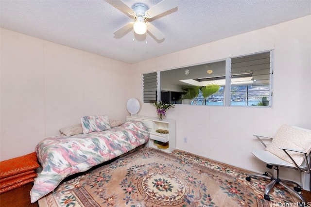 carpeted bedroom featuring ceiling fan and a textured ceiling