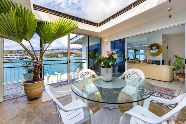 sunroom featuring a fireplace and a water view