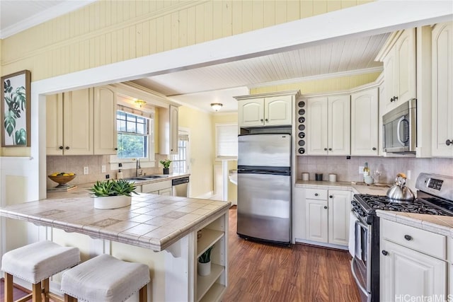 kitchen featuring tile countertops, a breakfast bar, dark hardwood / wood-style floors, appliances with stainless steel finishes, and kitchen peninsula