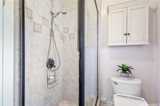 bathroom featuring a shower with door and toilet