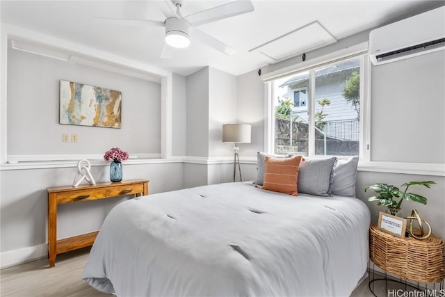 bedroom with a wall mounted air conditioner, light hardwood / wood-style flooring, and ceiling fan