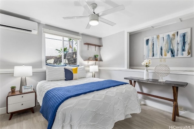 bedroom featuring ceiling fan, light hardwood / wood-style floors, and a wall mounted air conditioner