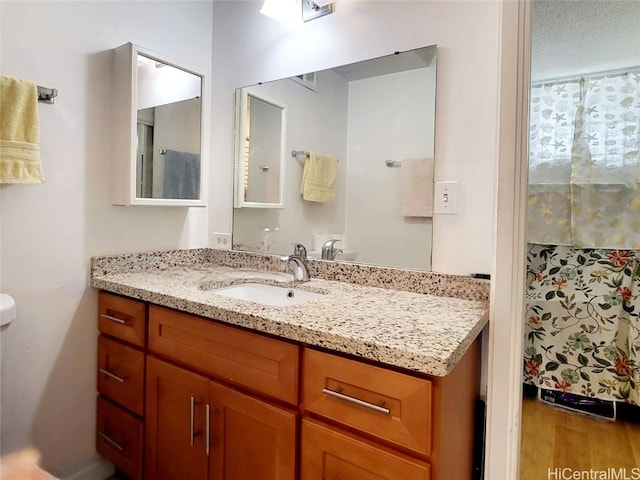 bathroom featuring hardwood / wood-style floors, vanity, and a textured ceiling