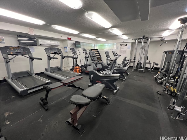 gym with a wall mounted AC and a textured ceiling