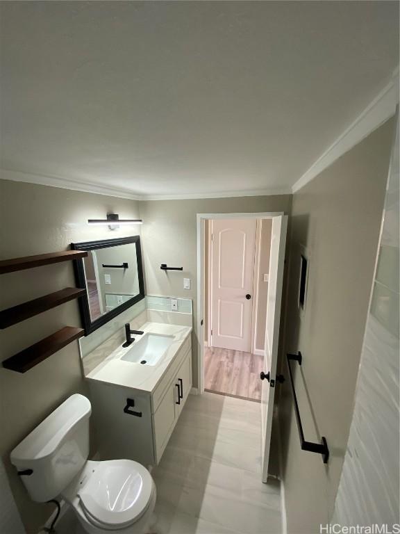 bathroom with toilet, vanity, tile patterned floors, and ornamental molding