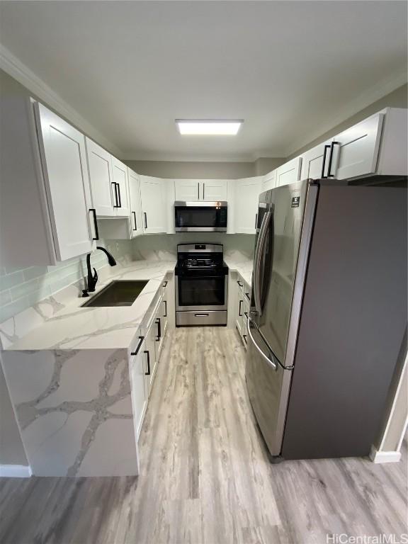 kitchen featuring white cabinetry, stainless steel appliances, light hardwood / wood-style floors, sink, and light stone counters