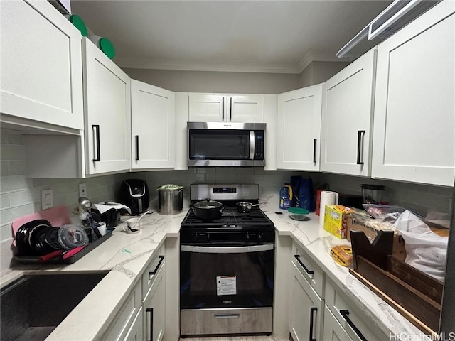 kitchen featuring tasteful backsplash, sink, crown molding, appliances with stainless steel finishes, and white cabinets