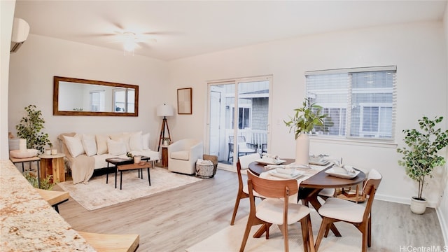 dining area with a wall mounted AC, ceiling fan, and light hardwood / wood-style flooring